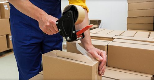 Office movers Melbourne — removalist sealing a cardboard box with packing tape during an office relocation.