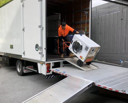 Office movers Melbourne — Jake Move removalist in orange uniform unloading office equipment down a hydraulic lift ramp.