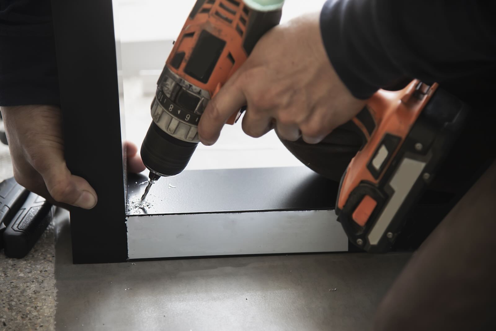 A technician using a power drill on an office furniture frame, demonstrating the expert disassembly and reassembly services offered for modular workstations.